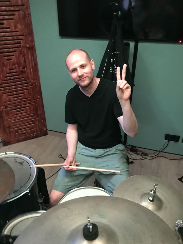 Mann der neben dem schlagzeug sitzt und peace macht