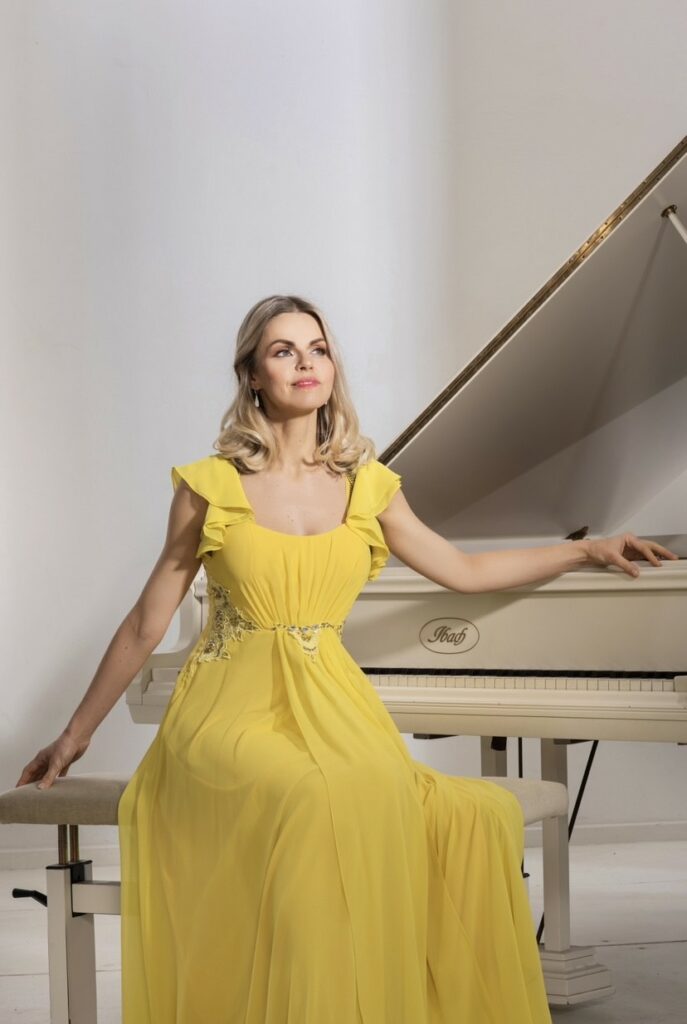 Frau im gelben Kleid sitzt neben einem klavier